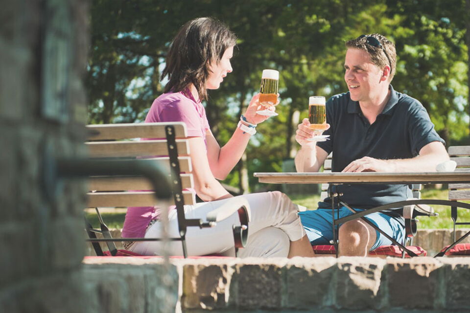 Biergarten Dorfschänke Paar sitzt im Biergarten der Dorfschänke und stößt mit einem Bier an