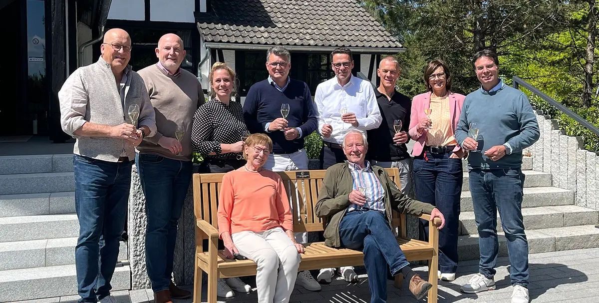 Parkbank Spende Gruppenbild mit Personen um gespendeter Parkbank vor dem Eingang des Hotels